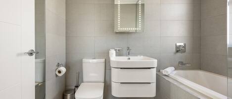 A modern bathroom with a toilet, sink, and bathtub.