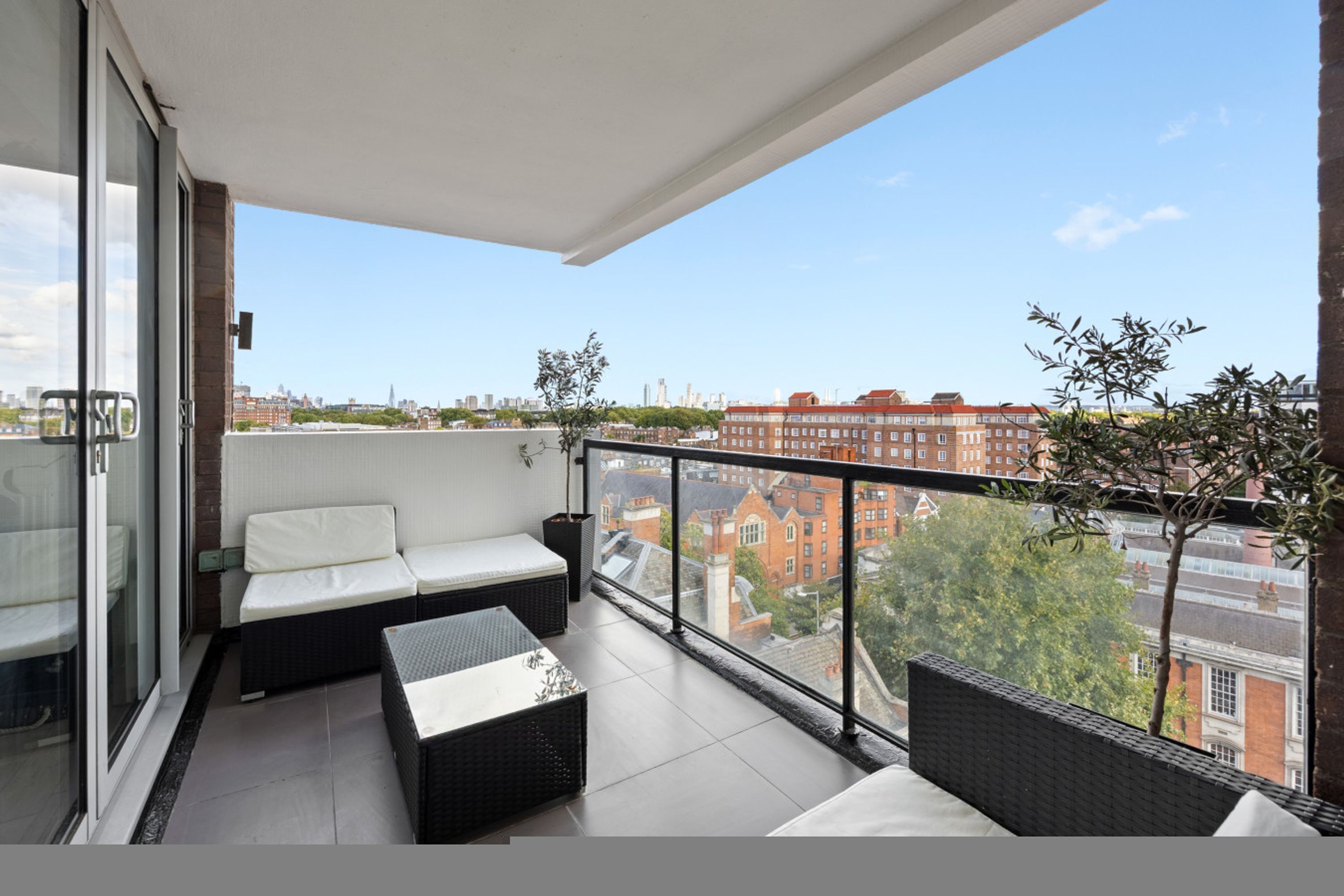 A balcony with a sofa, a small table, and a potted plant.