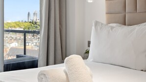 A hotel room with a bed, a view of the city, and a hanging light fixture. - Stunning Flat in Chelsea Kings Road With Balcony (London)