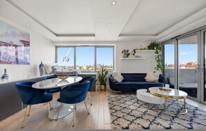 Ein modernes Wohnzimmer mit Essbereich, großen Fenstern und Blick auf die Stadt.