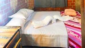 A room with a bed, a hanging light fixture, a wall-mounted air conditioner, and a brick wall. - Tarumã Challes 04, Complete chalet with balcony and barbecue, pets allowed. (Bonito)