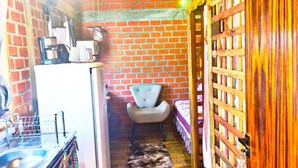 A compact kitchen with a refrigerator, sink, and a chair. - Tarumã Challes 04, Complete chalet with balcony and barbecue, pets allowed. (Bonito)