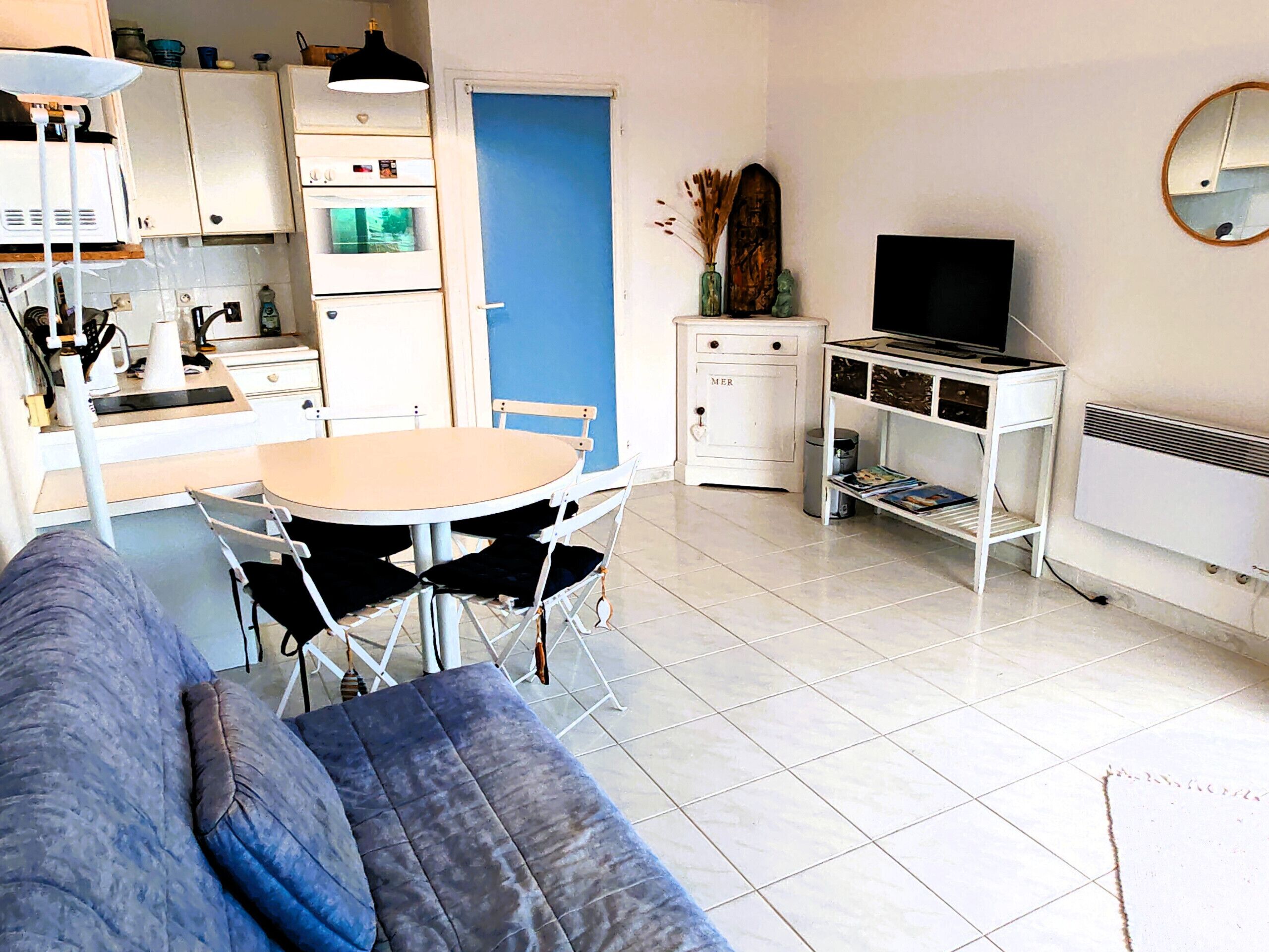A compact living space with a kitchenette, a dining area, a sofa, and a TV.