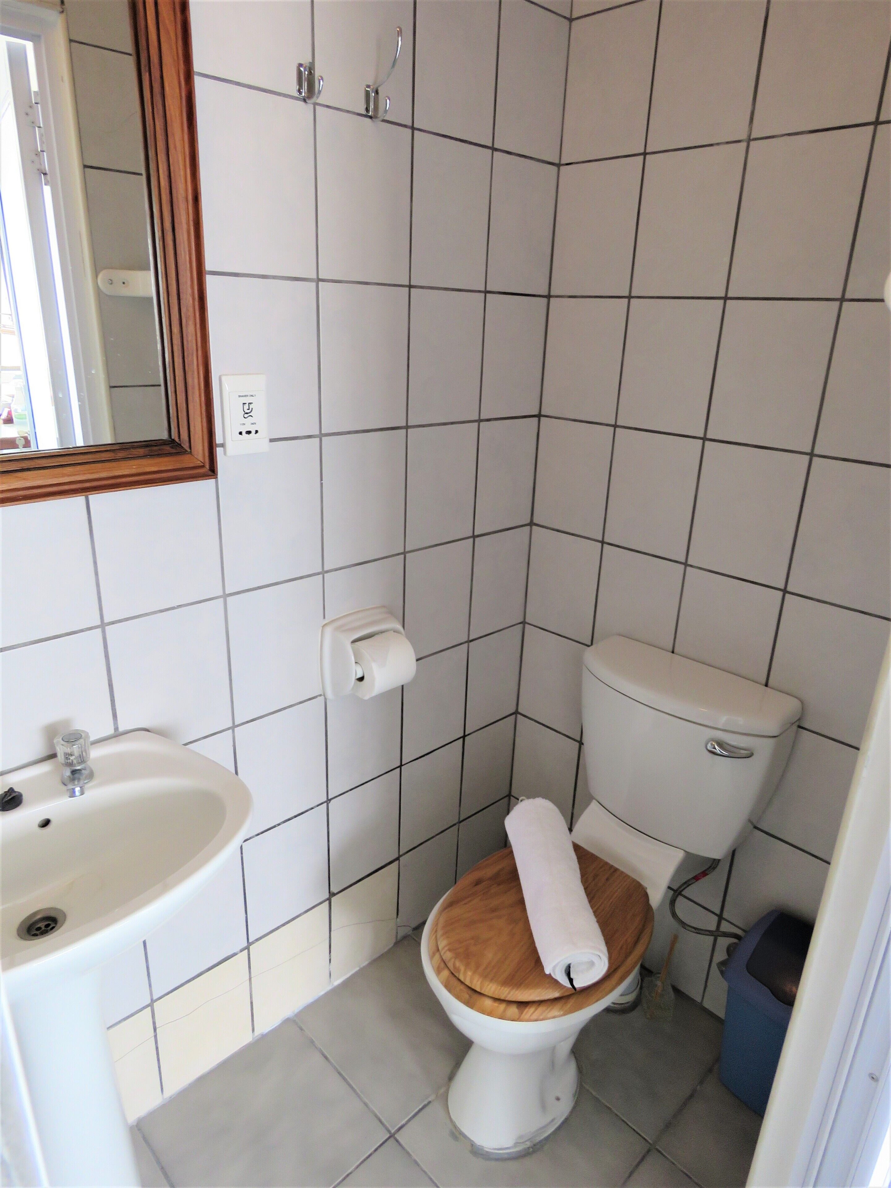 Et lille badeværelse med toilet, vask og spejl.
