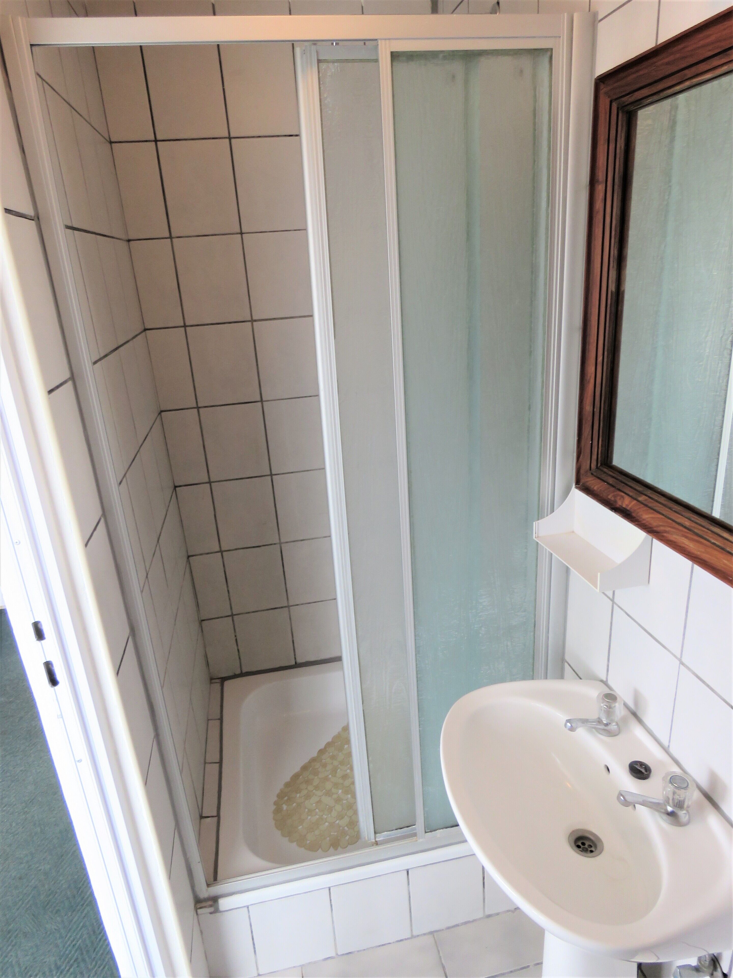 Une salle de bain avec une douche, un lavabo et un miroir.