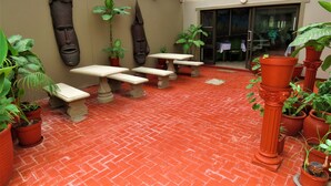 An outdoor patio with red brick flooring, stone tables and benches, and various potted plants. - Ngandu at Sea  (Walvis Bay)