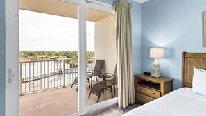 Ein Hotelzimmer mit Balkon, einem Bett, einem Nachttisch und einem Sessel.