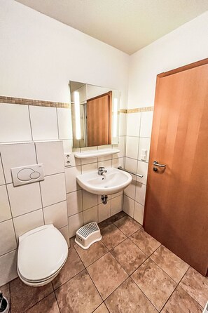 Ein kleines Badezimmer mit einem weißen Waschbecken, einer Toilette und einer Dusche.