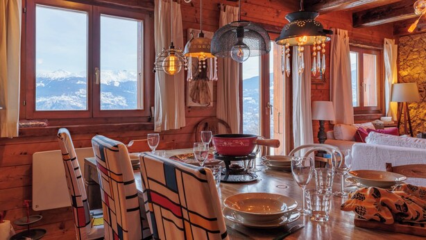 A wooden interior with a dining table set for four, a fireplace, and a view of snow-capped mountains. - Mayens du Rudet by Interhome (Erde)