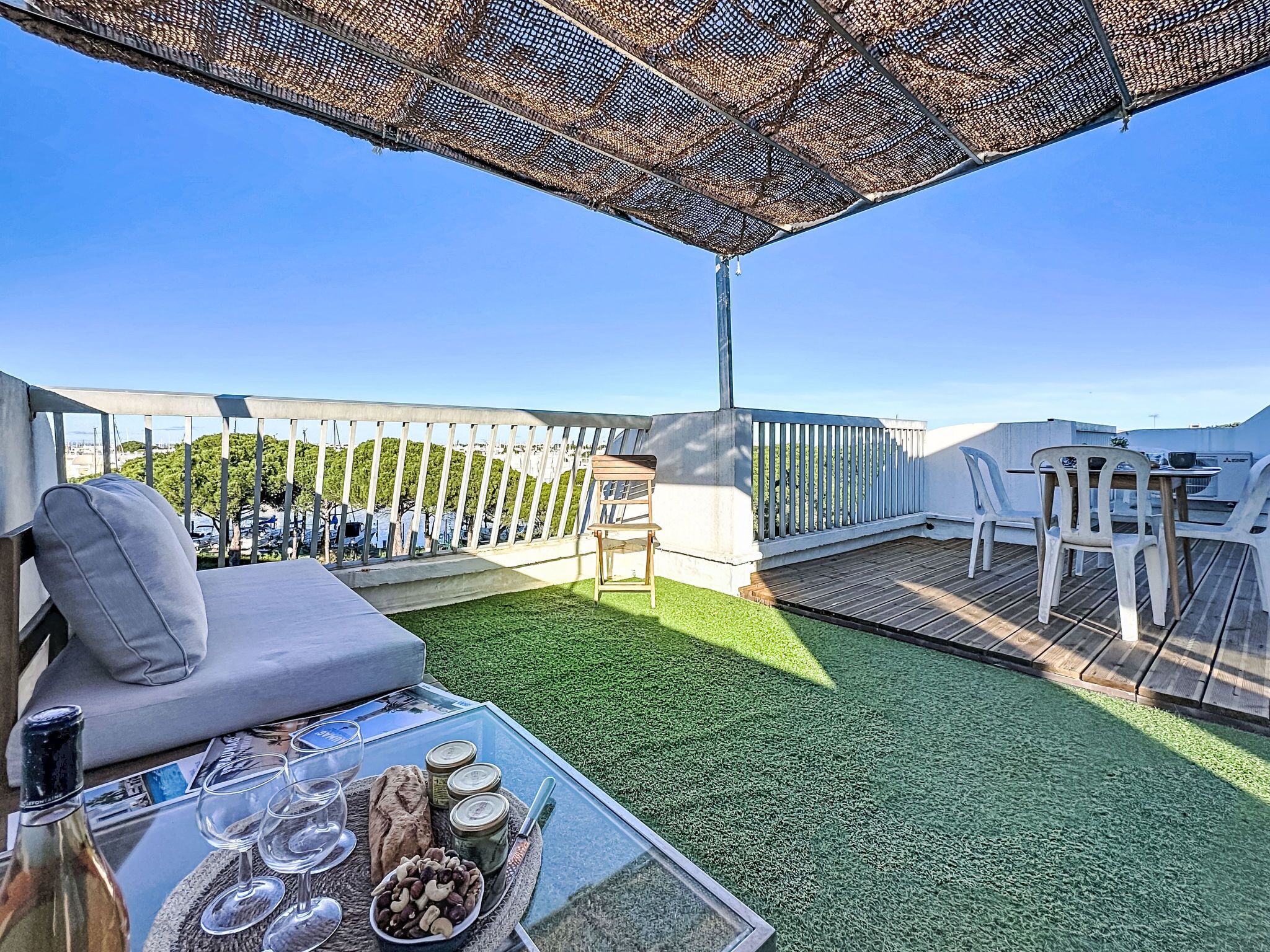 Une terrasse sur le toit avec une table en verre dressée pour les repas, un coin salon confortable et une vue sur le paysage urbain.