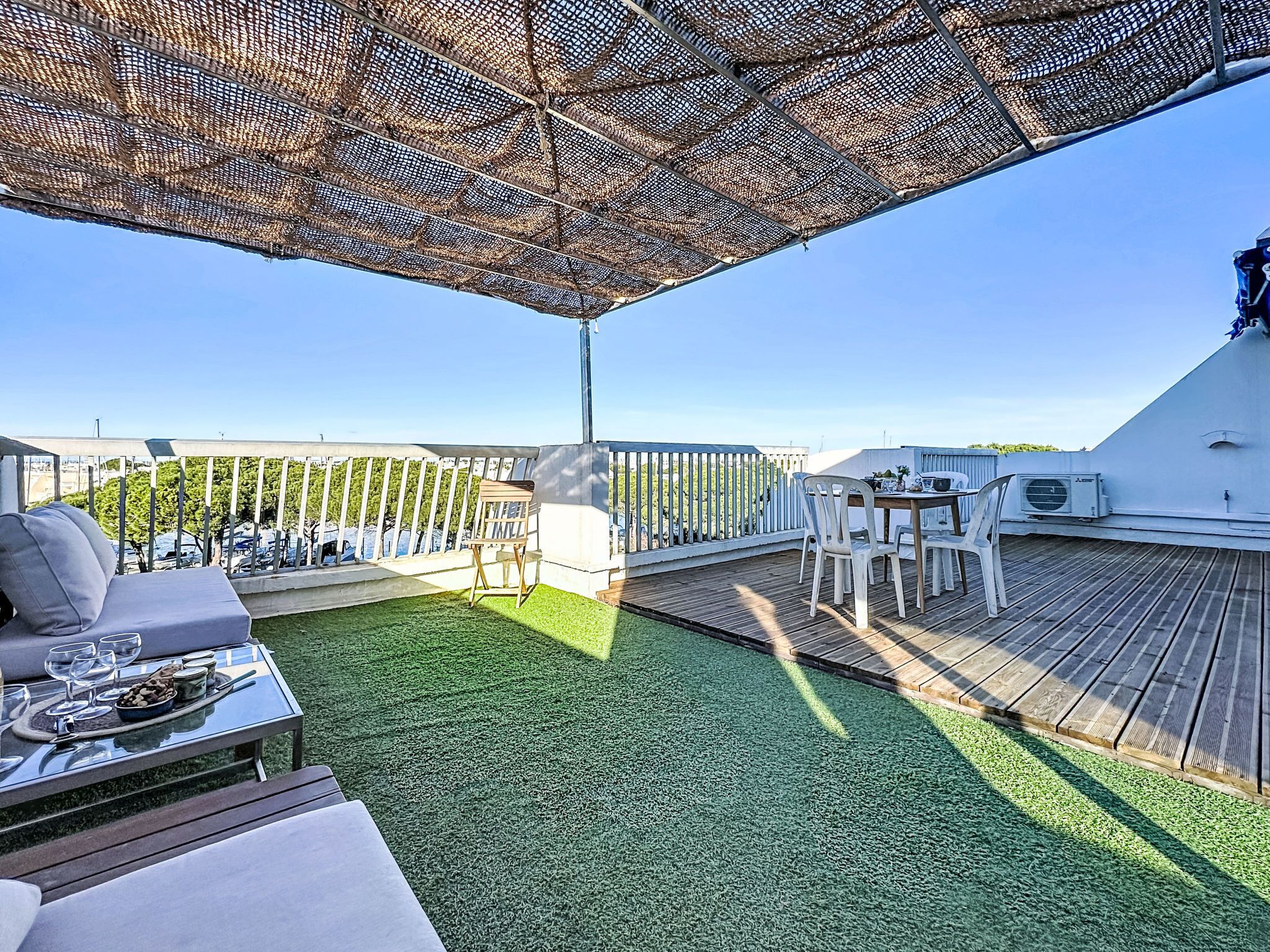 A rooftop terrace with a wooden deck, outdoor seating, and a view of the cityscape.
