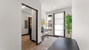 Ein modernes Interieur mit einem dunklen Holztisch, einem hellen Teppich und einer Topfpflanze.