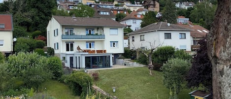 A residential area with houses, a green gate, and a hill with more houses in the background.