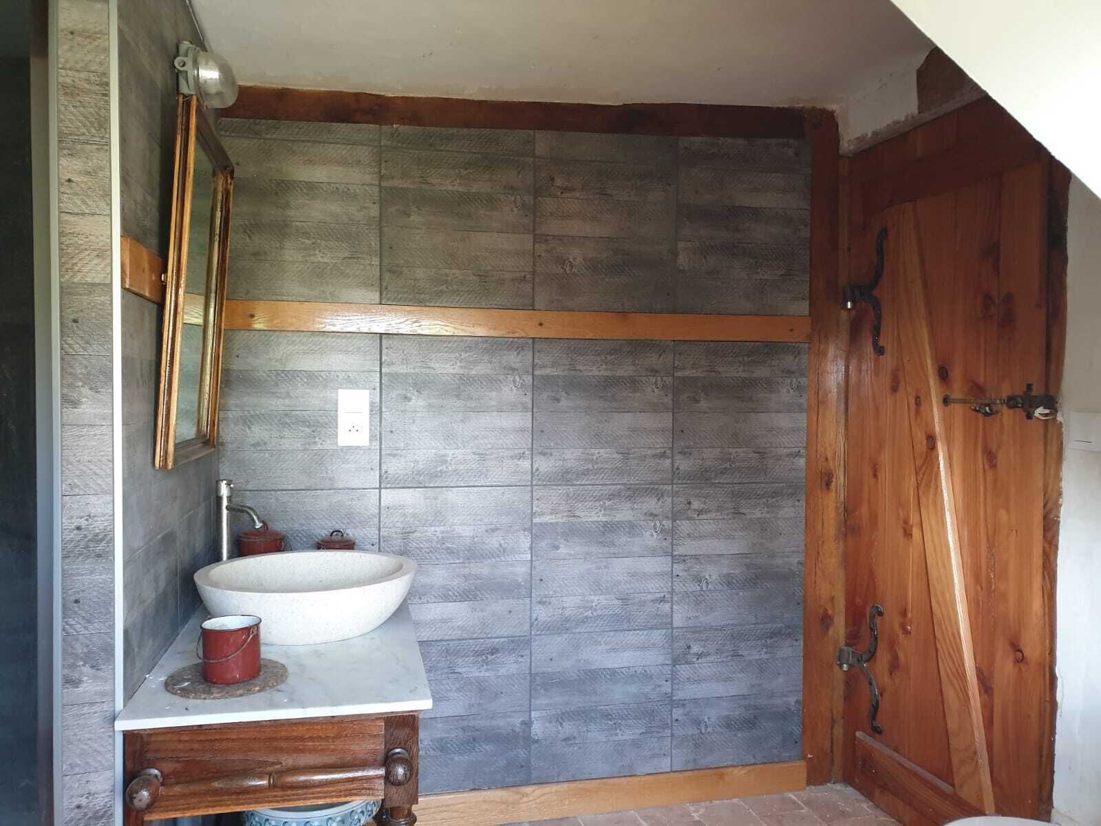 A bathroom with a wooden vanity, a large sink, and a wooden door.