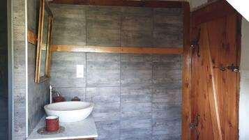 A bathroom with a wooden vanity, a large sink, and a wooden door.