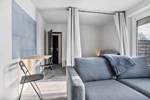 A modern living room with a grey sofa, a wooden table, and a folding chair. - Holiday Home 'Klein Aber Fein' with Shared Terrace and Wi-Fi (Worpswede)