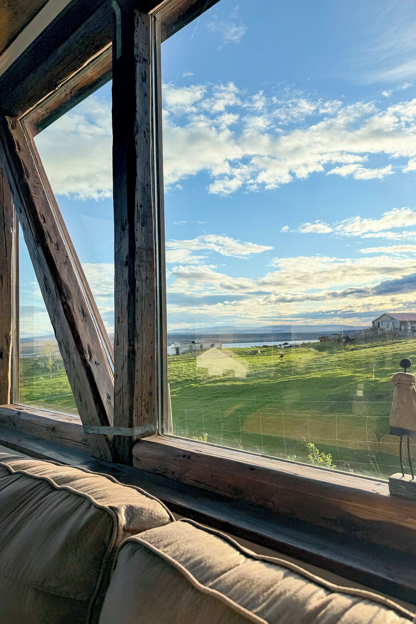 Una habitación con un ventanal grande que da a un paisaje verde y una masa de agua.