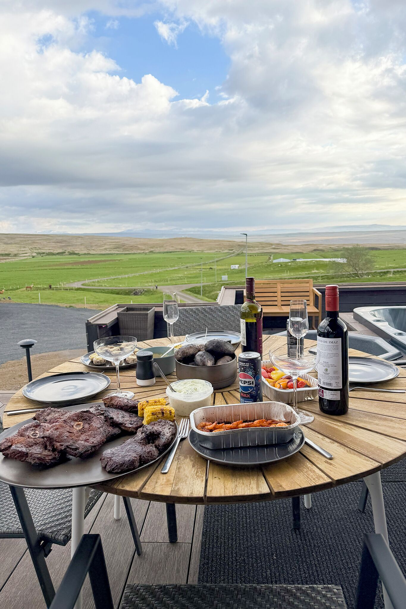 A dining table with various dishes, drinks, and a scenic view.