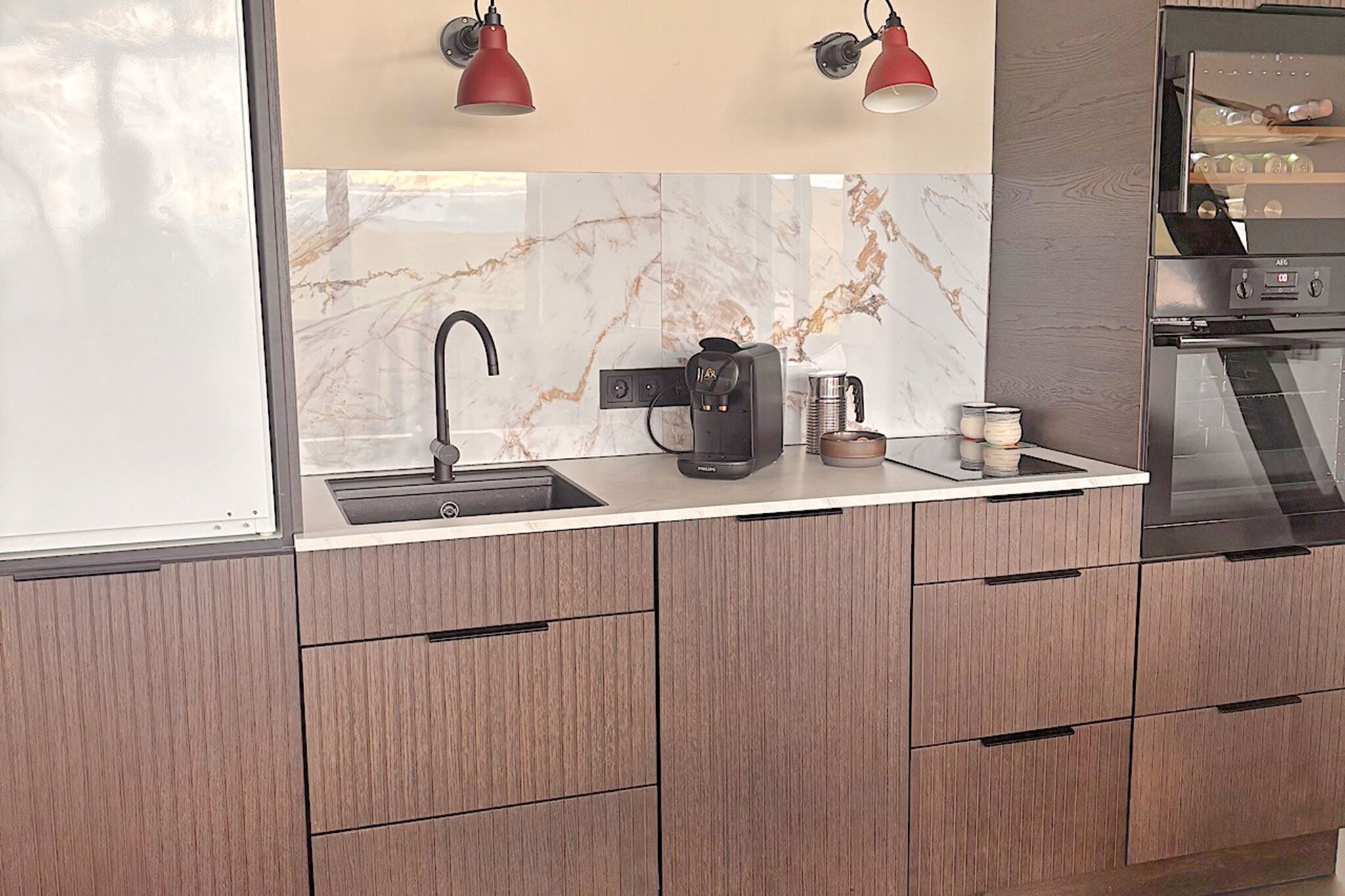 A modern kitchen with a sink, coffee maker, and cabinets.