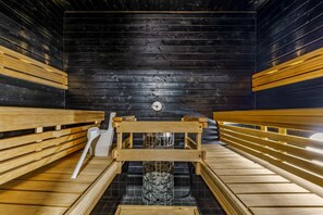 A sauna with wooden benches and a central stone structure. - Levin Kotka E1 | Modern 3BR Holiday Apt with Sauna & Parking Next to Ski Slopes (Levi)