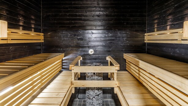 Uma sauna com bancos de madeira e um banco central com grade de metal.
