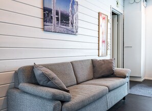 A grey sofa with multiple cushions, a framed picture on the wall, and a door to the right. - Spacious Two-Floor Apartment in Levi Center | Free Parking & Sauna (Levi)