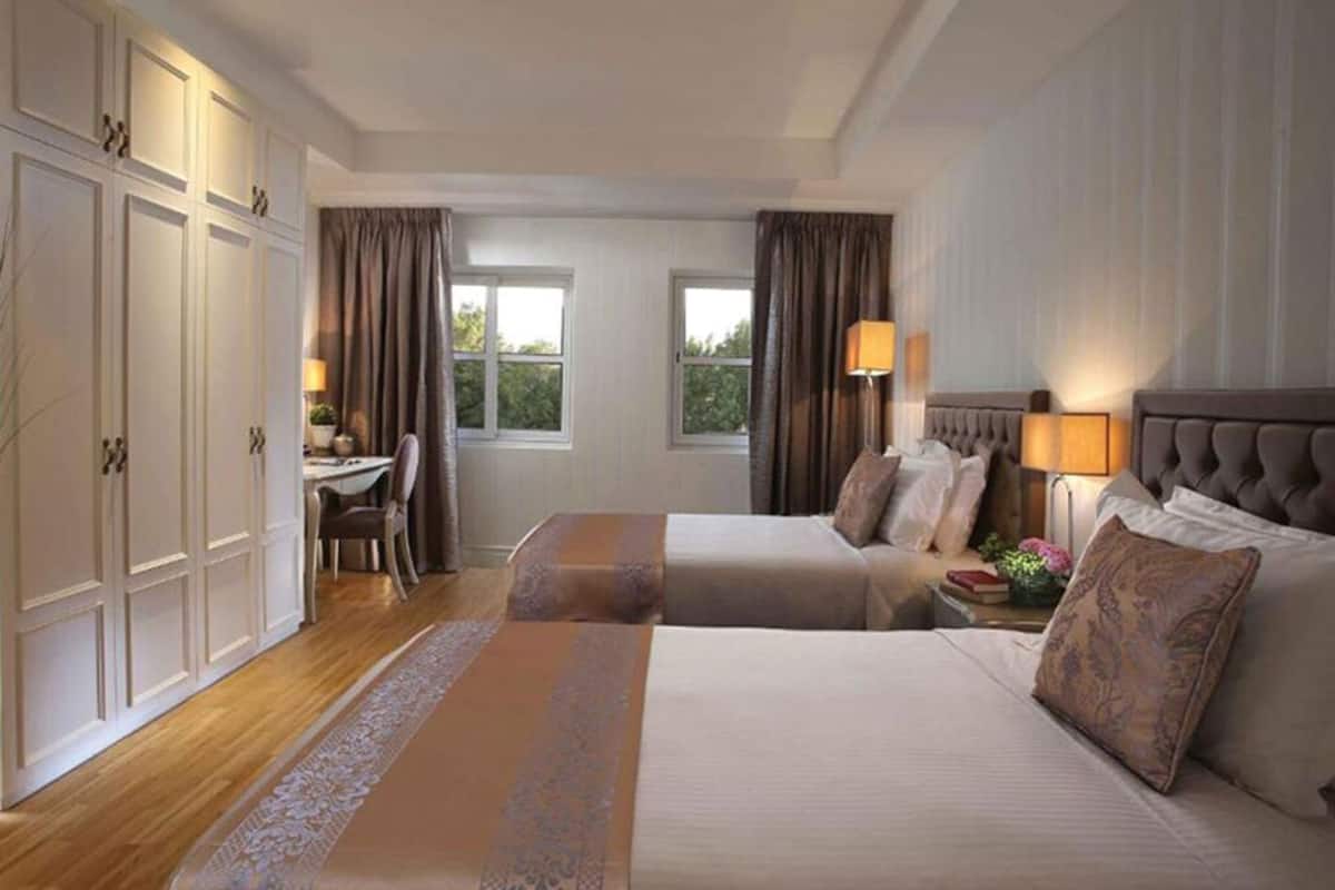Habitación de hotel con dos camas, un escritorio y una silla.