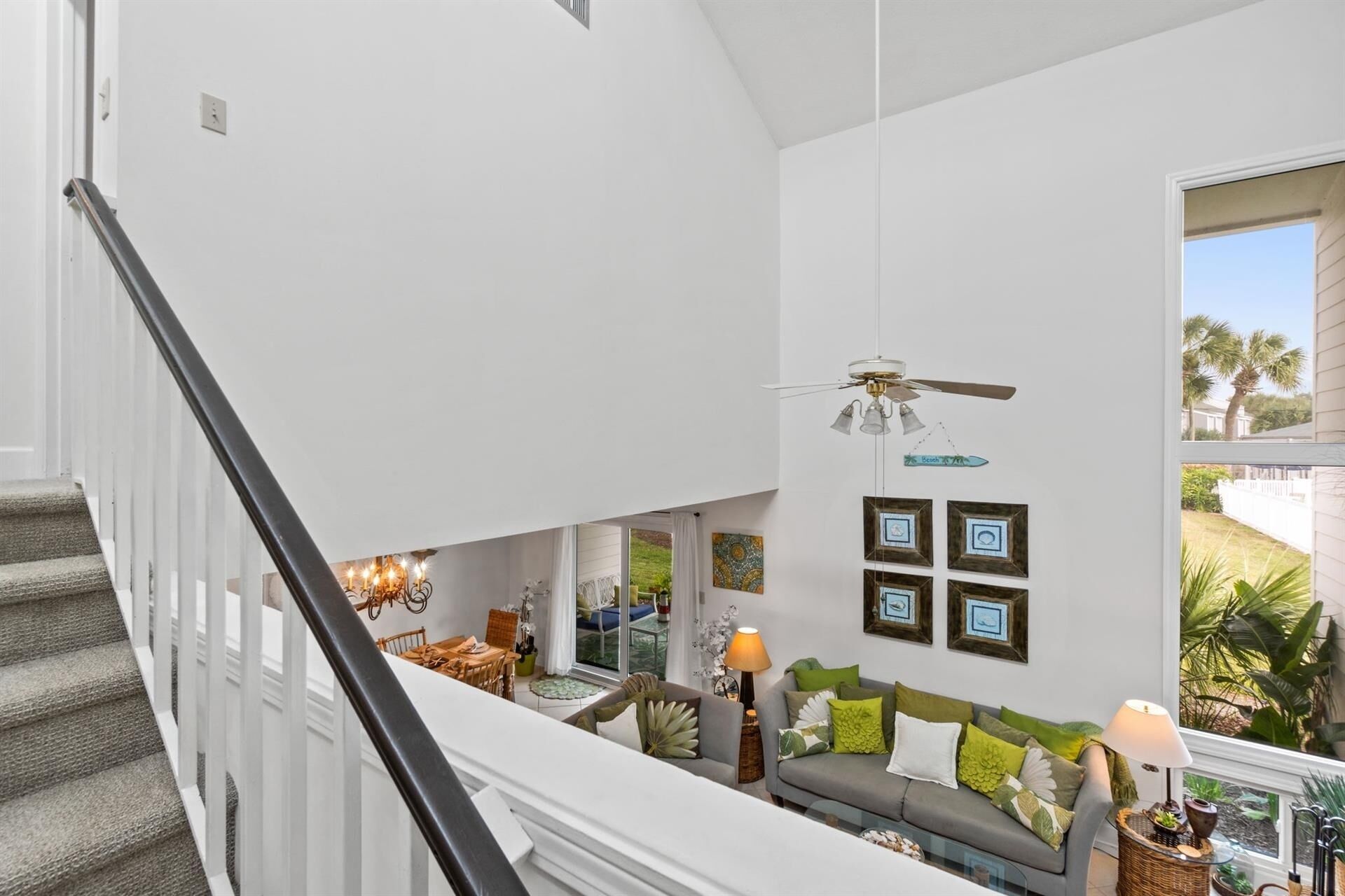 A spacious living area with a staircase, a ceiling fan, and a view of the outdoors.