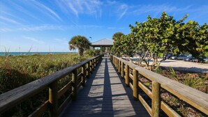A wooden boardwalk leading to a covered area with a view of the beach and ocean. - Gsr9220 2 Bedroom Home (Englewood)