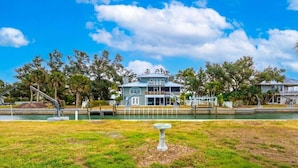 A waterfront property with a large house featuring a balcony, a dock, and a grassy lawn. - Gsr9220 2 Bedroom Home (Englewood)