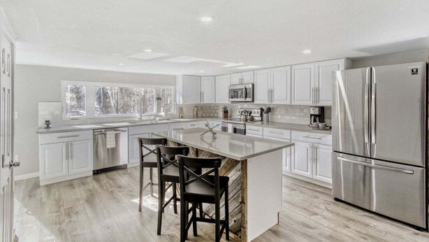 A modern kitchen with white cabinetry, stainless steel appliances, and a central island with chairs. - Black Hawk Getaway W/ Hot Tub 3 Bedroom Cabin (Black Hawk)