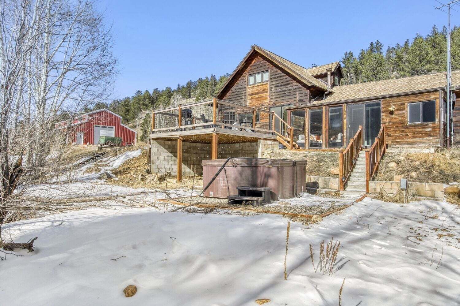 A wooden cabin with a covered patio and a hot tub.