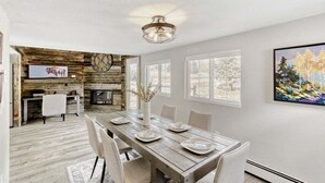 A dining area with a wooden table, chairs, and a vase with flowers. - Black Hawk Getaway W/ Hot Tub 3 Bedroom Cabin (Black Hawk)