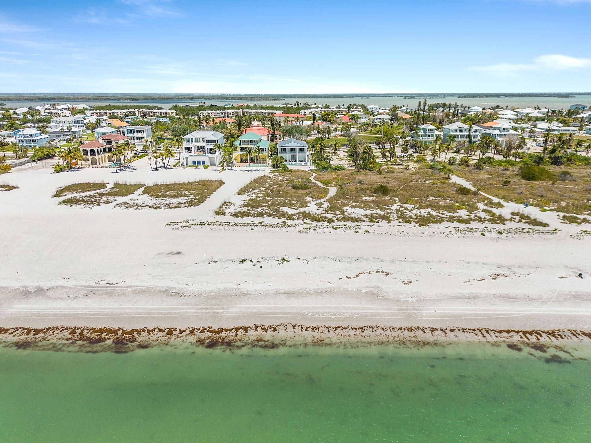 Un quartier résidentiel situé sur la côte, avec des maisons, une plage et une vue dégagée sur l’océan.