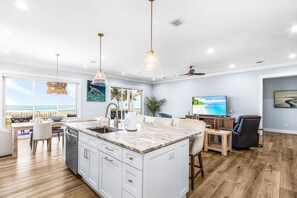 Amplia sala de estar con una isla grande, una mesa de comedor y un televisor.