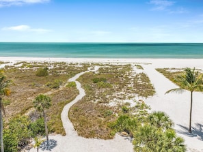 Una playa con un sendero arenoso, palmeras y una vista despejada del océano.