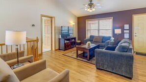 Ein Wohnzimmer mit Sofa, Sesseln, Couchtisch, Fernseher und Deckenventilator.