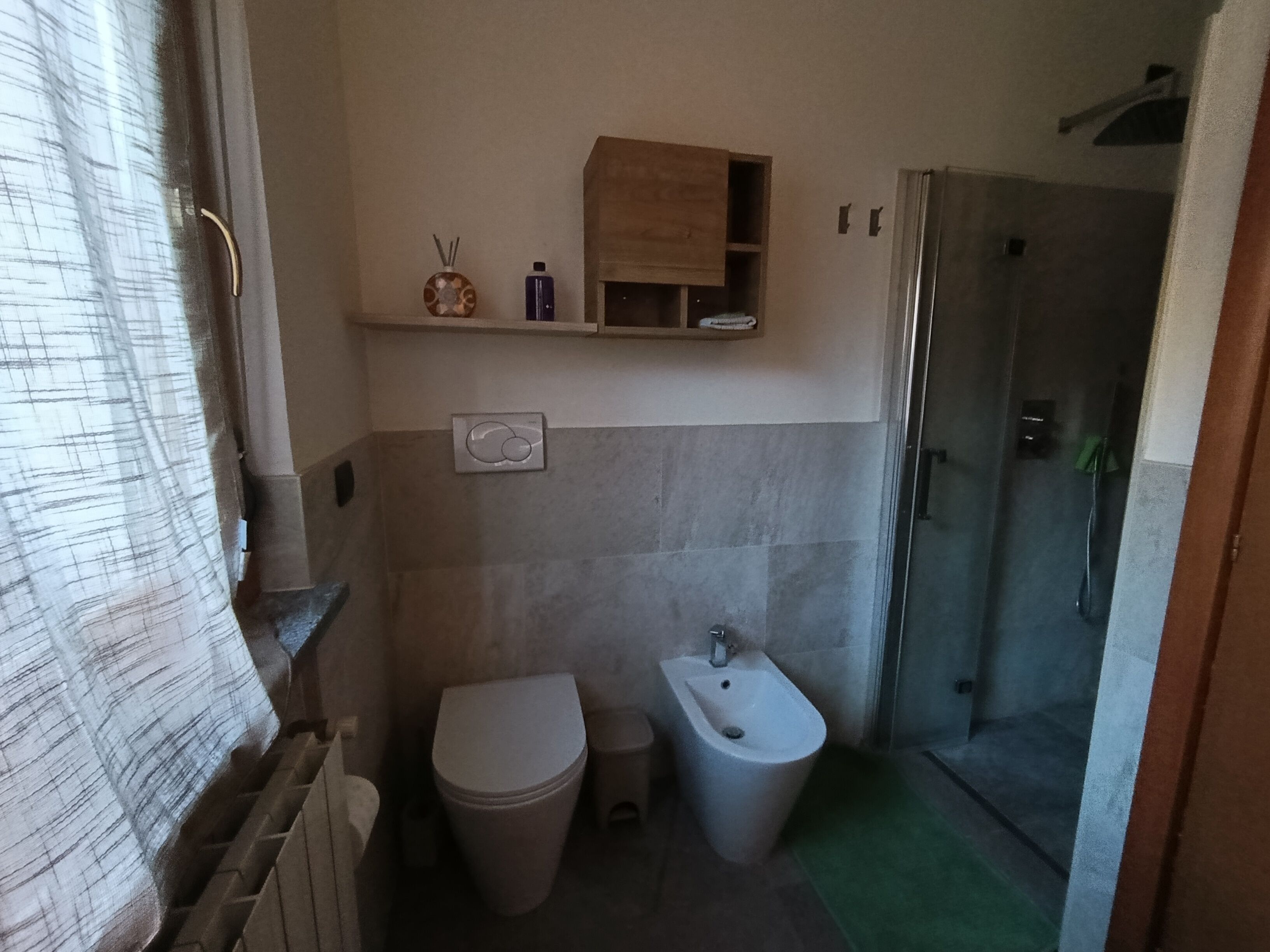 A compact bathroom with a toilet, bidet, and a shower stall.