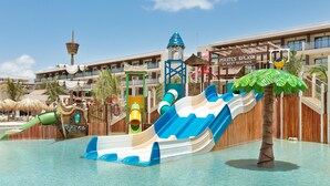 Un parc aquatique avec des toboggans, un palmier et un bâtiment sur lequel est affiché un panneau indiquant : « Pirates Splash by Best Serenade ».