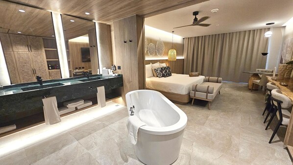 Une salle de bain moderne avec une baignoire sur pieds, un grand miroir et un meuble-lavabo doté d’un plan de travail foncé.
