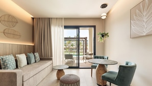 A modern living room with a sofa, ottoman, round table, and chairs. - Serenade Caribe Club Family Beach Resort – All Inclusive (Punta Cana)