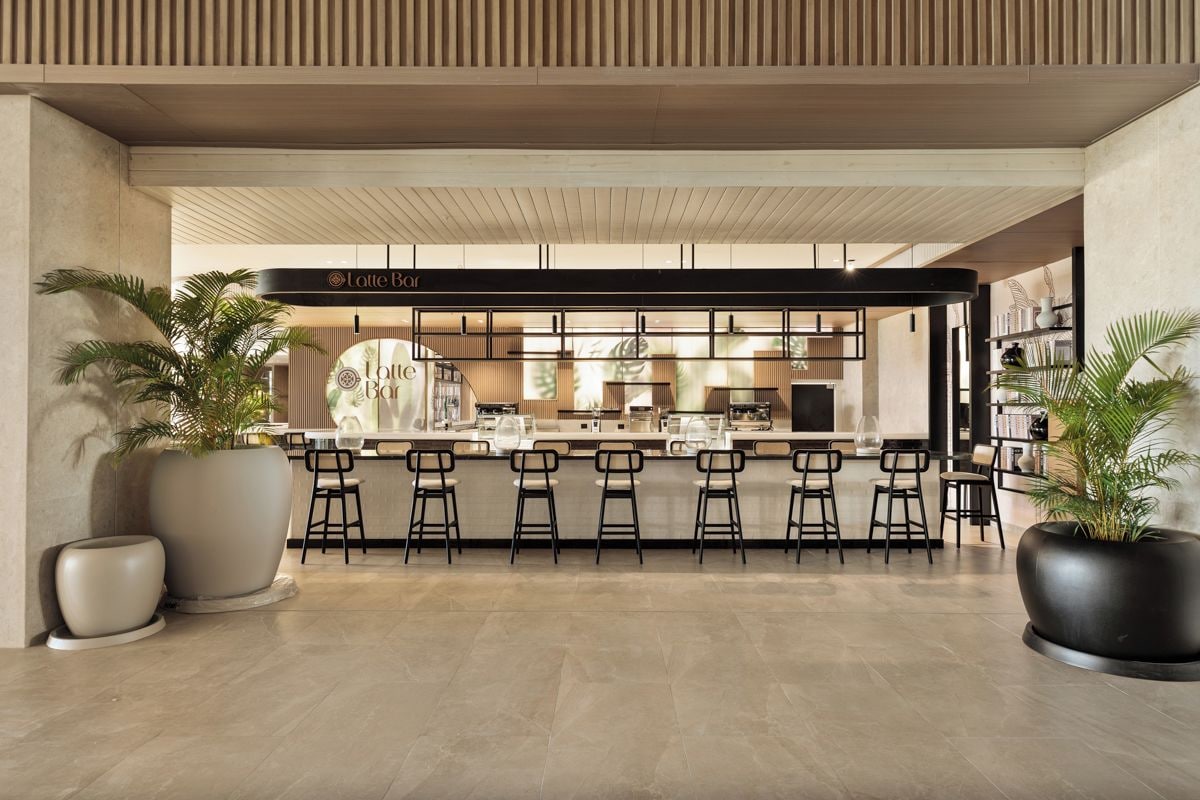 Een moderne bar met een toog, barstoelen en potplanten.