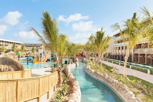 A resort with a swimming pool, palm trees, and a water slide.