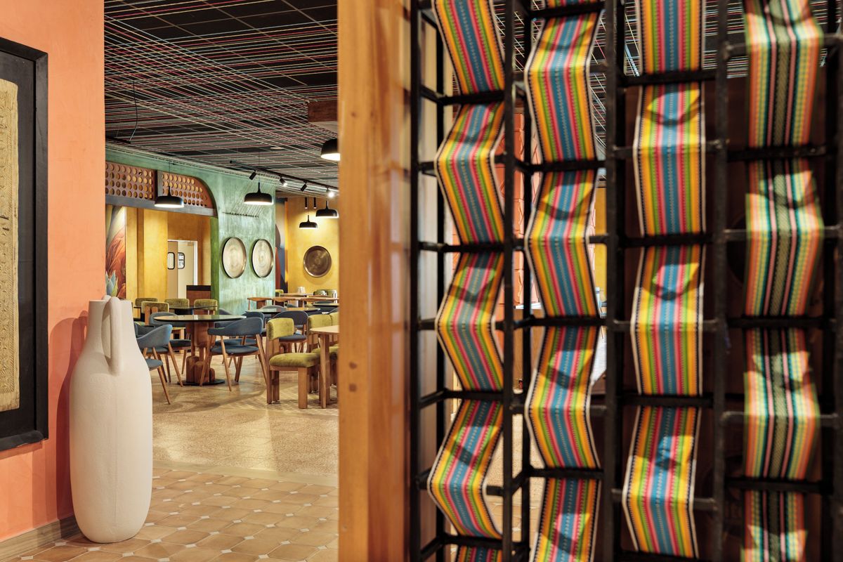 An interior with a dining area, a white vase, and a patterned wall.