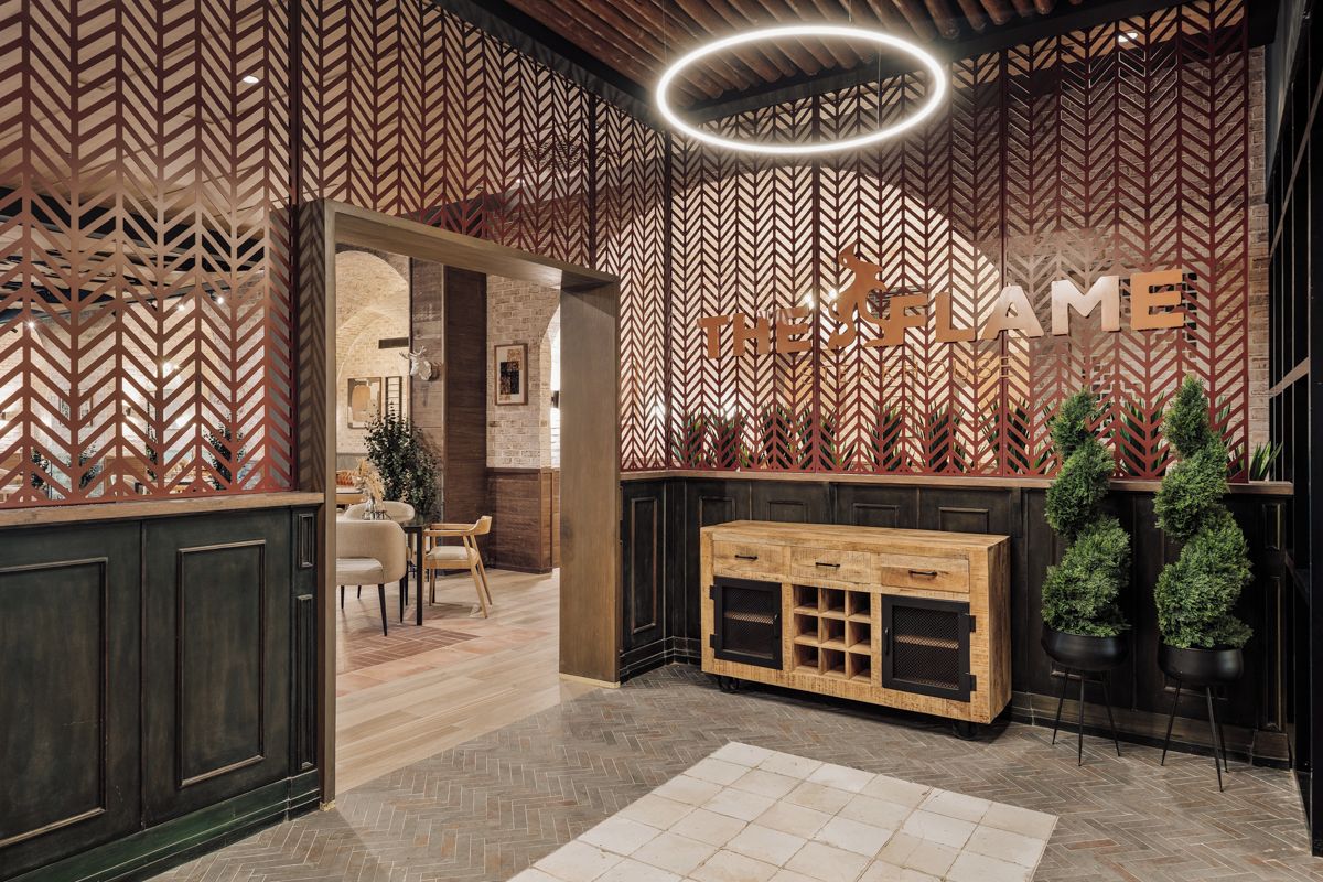 Un espace d’accueil avec un mur orné d’un motif en chevrons, un comptoir d’accueil en bois et un luminaire circulaire placé au-dessus.