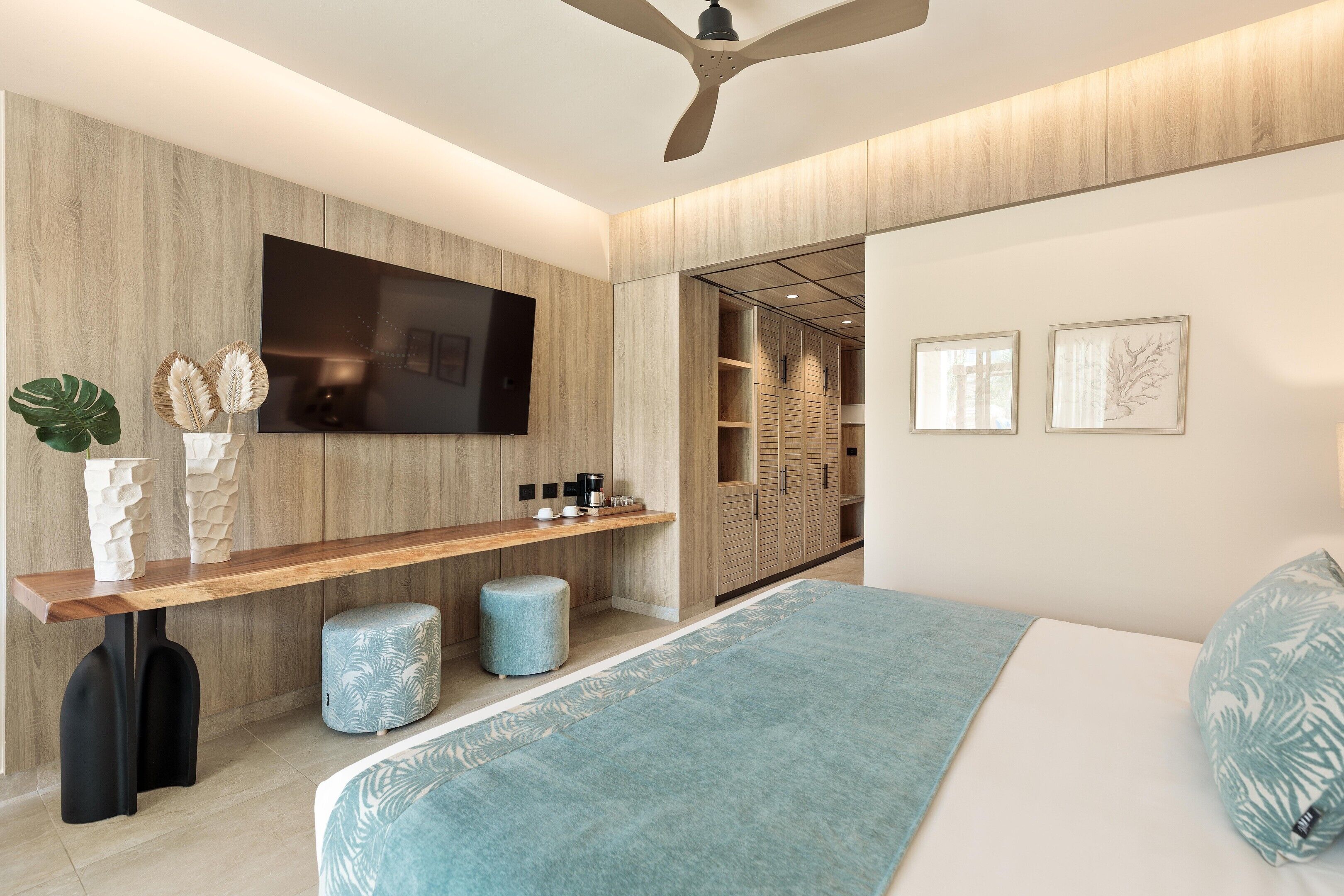 A modern bedroom with a bed, a TV, a wooden desk, and a closet.