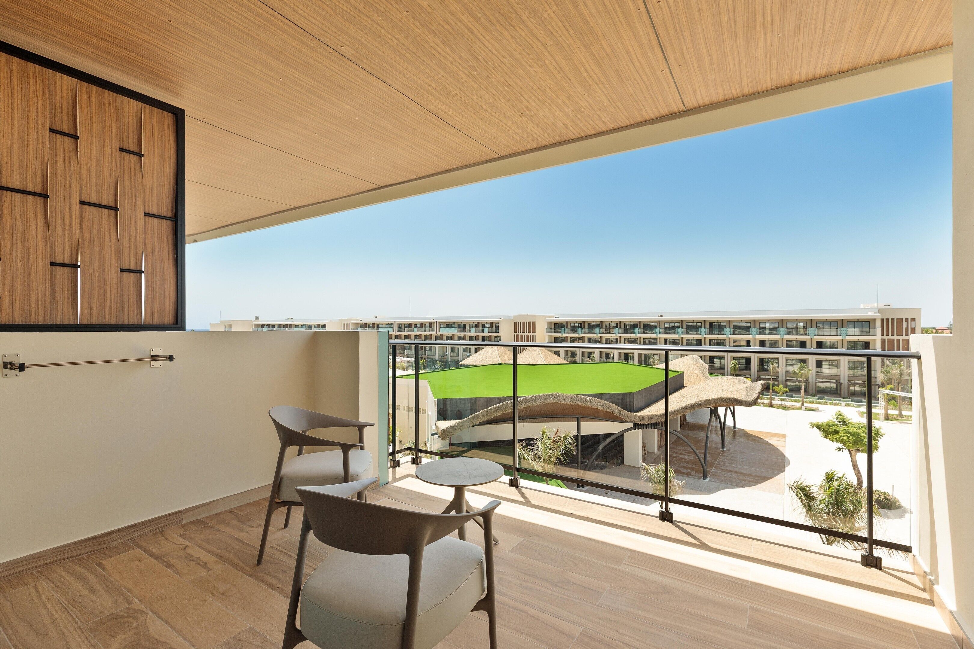 Een balkon met uitzicht op een sportveld, een tafel en twee stoelen.