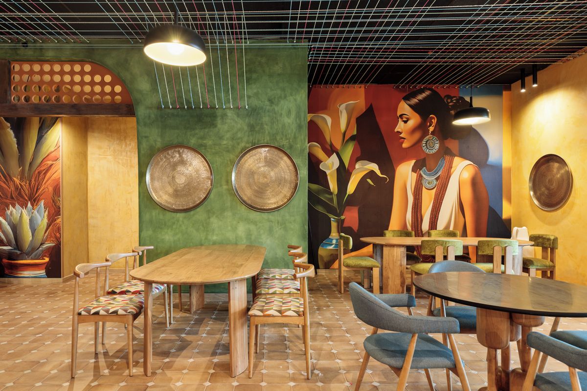 A restaurant interior with wooden tables and chairs, a mural on the wall, and a ceiling with a grid pattern.