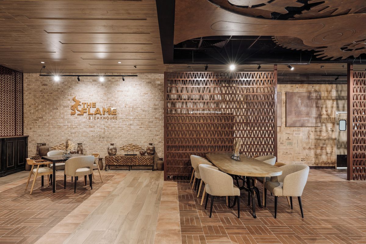 A restaurant interior with a brick wall, wooden ceiling, and a dining area with tables and chairs.