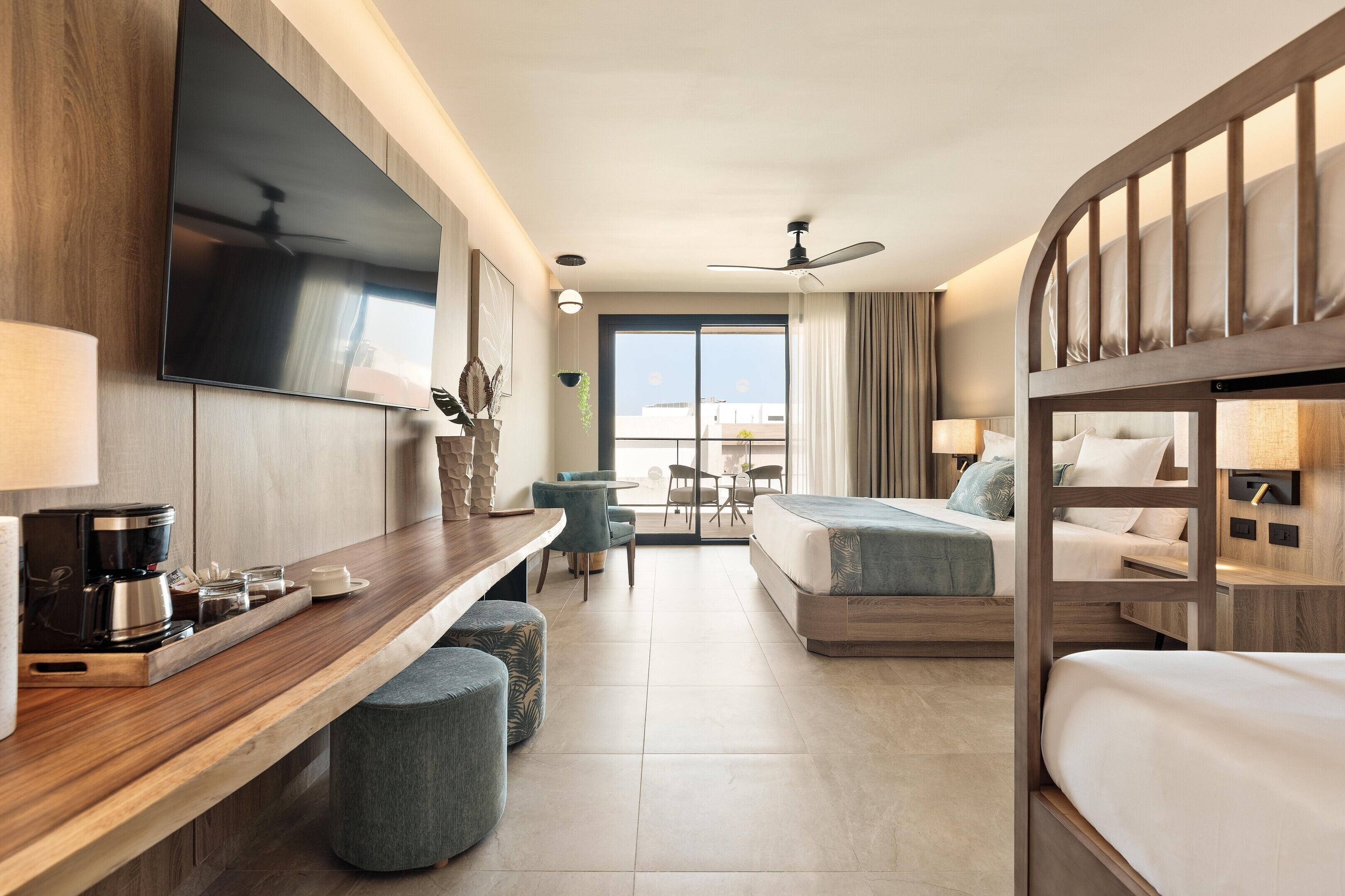 Een hotelkamer met een bed, een bureau met koffiezetapparaat, een televisie en een balkon met uitzicht.